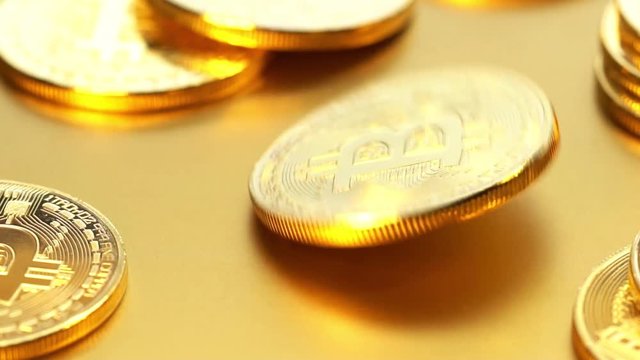 Coin golden bitcoin rotation, twist and falls on a golden background. Slow motion video 120 fps.