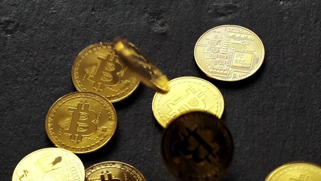 Coins golden bitcoin fall and twist on the graphite surface. Slow motion video. 120 fps.