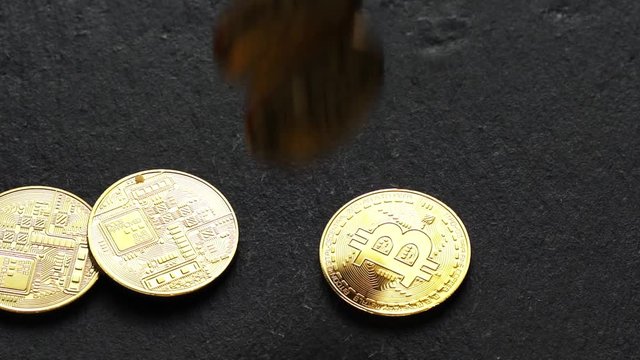 Coins golden bitcoin fall and twist on the graphite surface. Slow motion video. 120 fps.