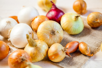 assorted fresh onions on a wooden table. wallpaper for grocery shopping and cooking food concept
