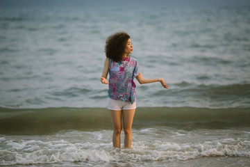 Fototapeta na wymiar Young mixed race woman walking on the sea beach. Film color style.