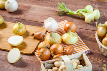 assorted fresh onions on a wooden table. wallpaper for grocery shopping and cooking food concept