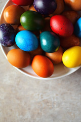 Colorful boiled Easter eggs in white plate on grey background.