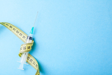 Syringe with a needle and yellow measuring tape. Injections for body beauty and weight loss. Drug...