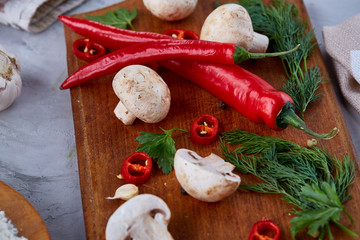 Vegetables on cutting board, plate with salt over white textured background, close-up, selective focus.