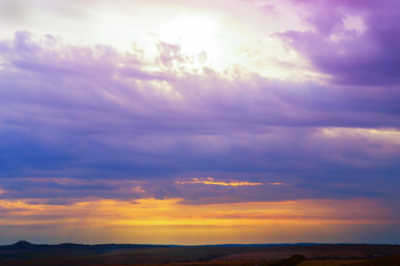 sunset in cloudy sky over field