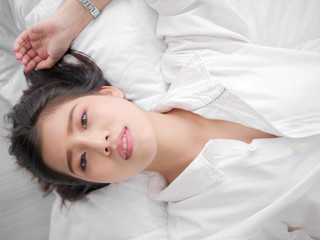 Fototapeta na wymiar Happy Asian woman lying on bed, closed up.