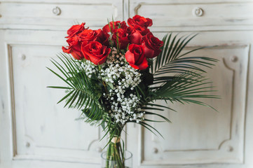 Bouquet of red roses on furniture in wood with white tint