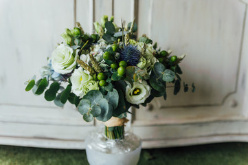 Bouquet of bridal flowers, in green tones, on white wood furniture