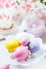 Easter eggs in pastel color on a white cake stand, bunny cupcakes and flowers. Festive  light background