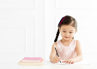 little girl with book writing to notebook at home.