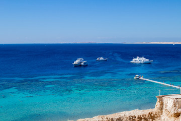 Dark blue clean bay water panorama on the Red Sea shore, spectacular landscape with resort yachts