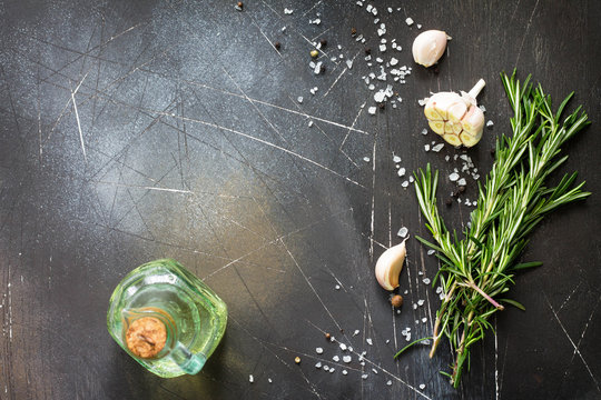 Spices, olive oil  and herbs on a dark stone or slate table. Ingredients for cooking. Food background. Copy space, top view flat lay background.