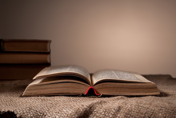 unfolded book on the surface with burlap and stack of books in the background