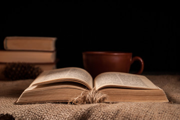 unfolded book on the surface with burlap and pine cone and a cup