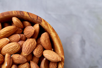 Bowl of almonds on white textured background, top view, close-up, selective focus.