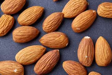 Raw almond on baking tray over white textured background, selective focus, shallow depth of field.