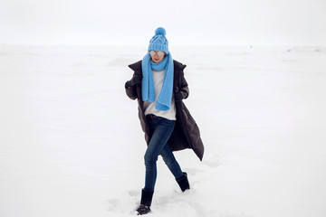 girl running in a snowy field in a jacket and sunglasses