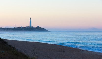 Splendid sunrise at Zahora Beach with intense blue water and Trafalgar Lighthouse on the background...