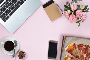 Top view of office gadgets, coffee, mobile phone and pizza on a pink background, flat lay