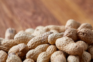 Unpeeled peanuts on a wooden background, top view, selective focus, shallow depth of field.