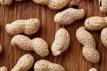 Unpeeled peanuts on a wooden background, top view, selective focus, shallow depth of field.