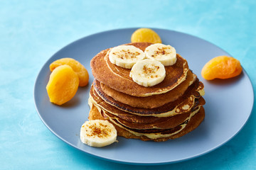 Pile of homemade pancakes with honey and walnuts on blue background, selective focus