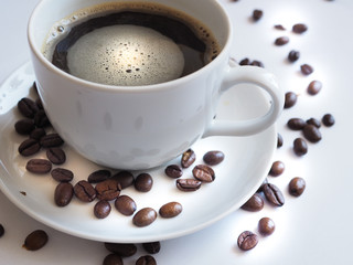 coffee with a white cup and brown beans on a saucer.