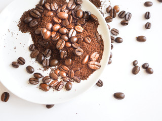 brown coffee beans and ground coffee on a white cup.