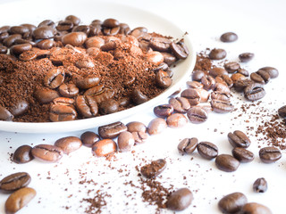 brown coffee beans and ground coffee on a white cup.