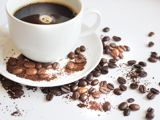 brown coffee beans and ground coffee on a white cup.