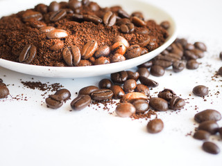 brown coffee beans and ground coffee on a white cup.