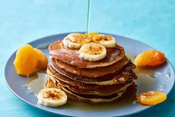 Pile of homemade pancakes with honey and walnuts on blue background, selective focus