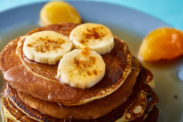 Pile of homemade pancakes with honey and walnuts on blue background, selective focus