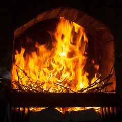 A bright and hot flame  in the opening of a stone fireplace