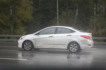 Fototapeta na wymiar Drive white car in rain on asphalt wet road. Clouds on the sky