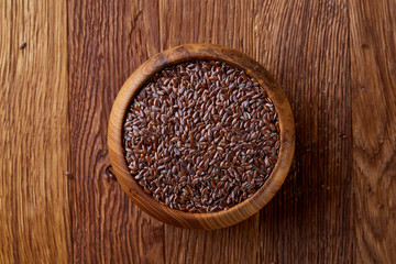 Obraz na płótnie Canvas Flax seeds in a plate on wooden background, top view, close-up.