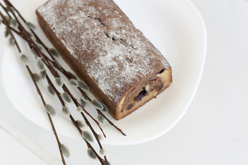 Кекс лежит на белой тарелке рядом с ветками вербы