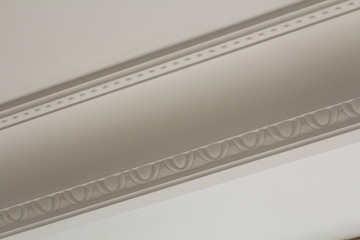 Ornamental white molding decor on ceiling of white room close-up detail. Interior renovation and...