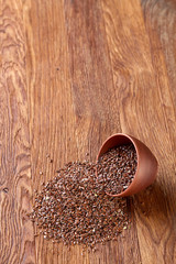 An overturned ceramic bowl with linseeds on a rustic background, close-up, shallow depth of field, selective focus