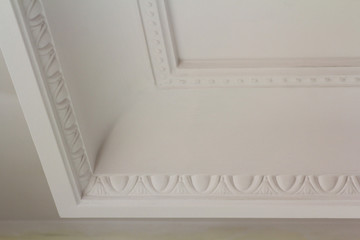 Ornamental white molding decor on ceiling of white room close-up detail. Interior renovation and...