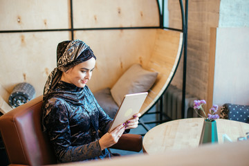 Portrait of beautiful Arabic Muslim girl using tablet in cafe