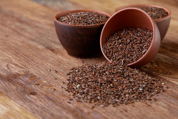 An overturned ceramic bowl with linseeds on a rustic background, close-up, shallow depth of field, selective focus