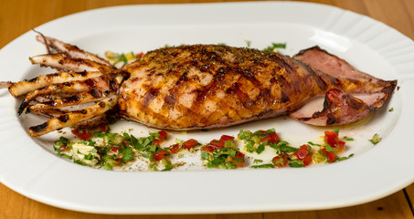 Grilled whole squid on a BBQ with Greek Spice. Top view. Wooden background. 