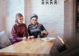 two Pretty caucasian muslim woman drinking tea in cafe