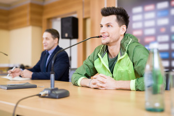 Handsome young football player wearing track jacket expressing his point of view concerning played...