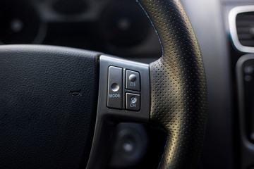 multimedia control buttons on the steering wheel in the modern black interior of the car.