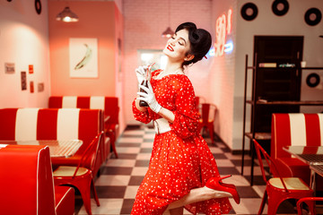 Pinup girl drinking carbonated drink in retro cafe