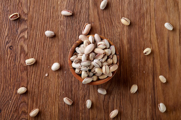 Almonds in brown bowl on wooden background, top view, selective focus.