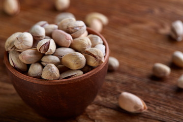 Almonds in brown bowl on wooden background, top view, selective focus.